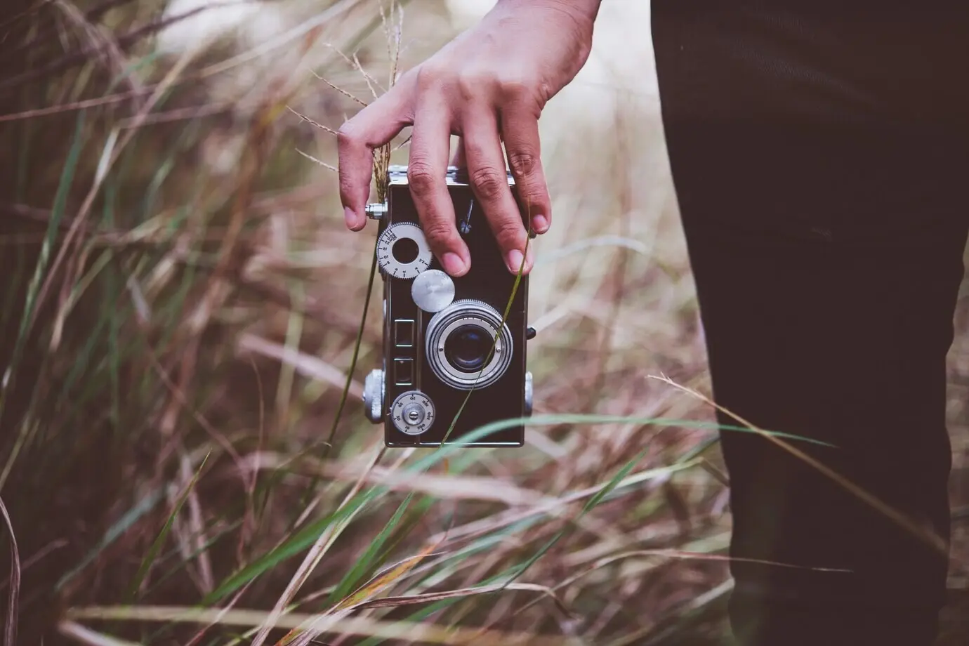 Junge Hipster-Frau fotografiert mit einem analogen Vintage-Fotoapparat auf einem sommerlichen Feld. Frauen-Lifestyle-Konzept.