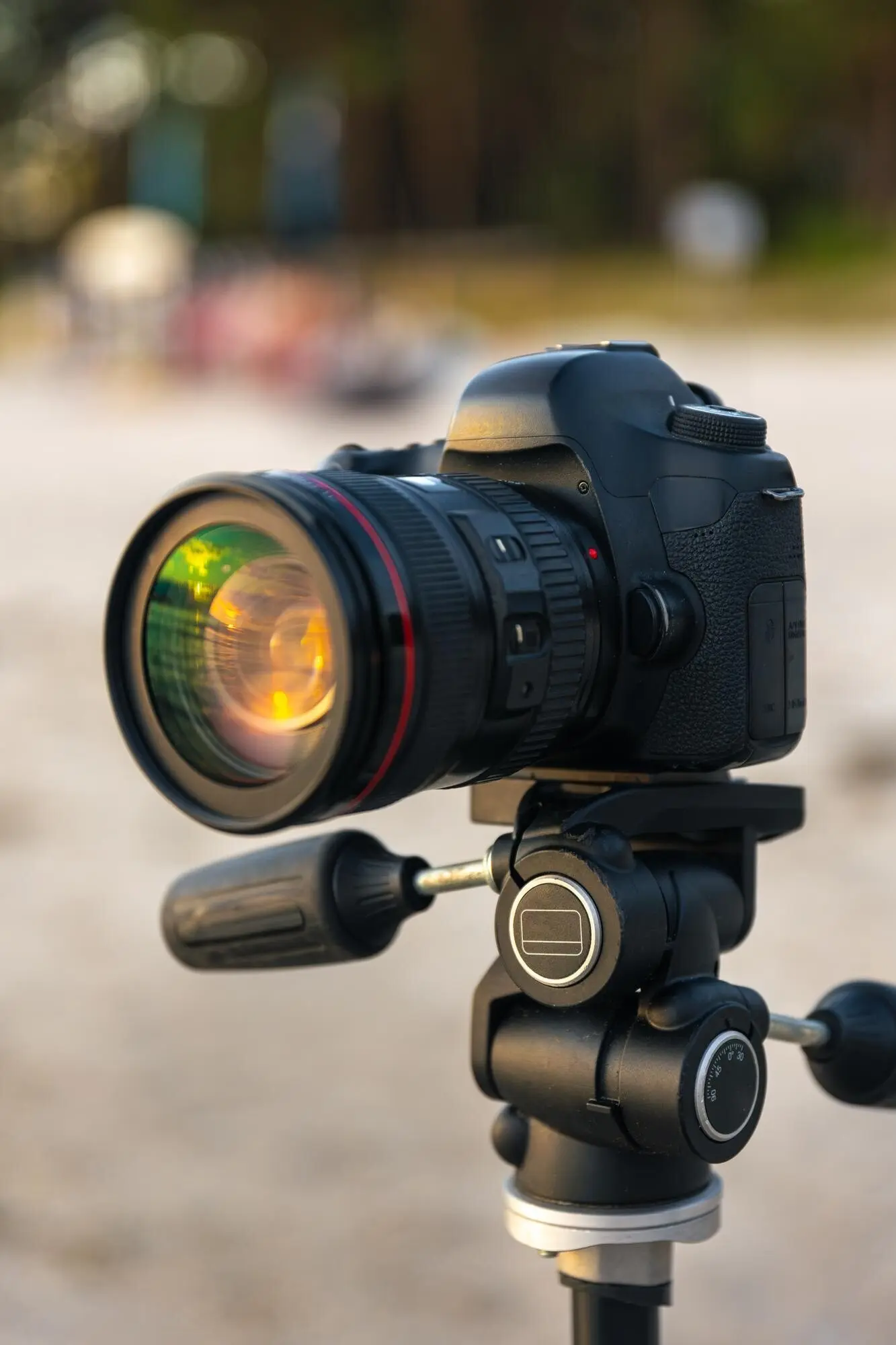 Nahaufnahme einer Kamera mit Objektiv auf einem Stativ am Sandstrand.